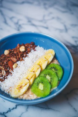 Vejetaryen kafeteryasında sağlıklı kahvaltı. Öğle yemeği için nefis vejetaryen yemeği. Kaynamış beyaz pirinç, kepekli yulaf lapası, dilimlenmiş kivi & muz, fındık & badem, mavi seramik kasede servis edilen mavi seramik kase. 