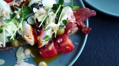 Kahvaltı için nefis bir sandviç. Egzotik bruschetta ekmeği haşlanmış yumurta, jambon dilimi, mikro yeşil lahanalar, kafede öğle yemeği için hazırlanmış kurutulmuş domatesler. Doğal malzemelerle pişirilmiş lezzetli yemekler.