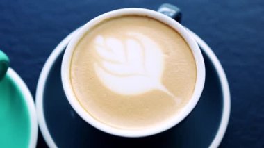 İtalyan kafesinde kahvaltı için hazırlanmış kapuçino kahveli iki seramik fincan. Yukarıdan masanın üzerine çekilmiş bardaklı latte içeceği ile görüntülere zum yapıyorum. 
