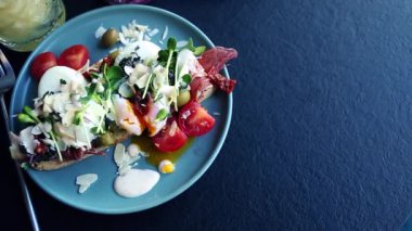 Kahvaltı için nefis bir sandviç. Egzotik bruschetta ekmeği haşlanmış yumurta, jambon dilimi, mikro yeşil lahanalar, kafede öğle yemeği için hazırlanmış kurutulmuş domatesler. Doğal malzemelerle pişirilmiş lezzetli yemekler.