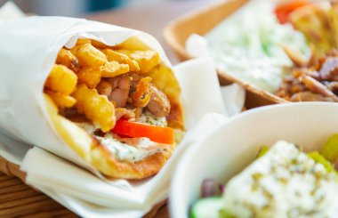 Yunan fast food restoranı teslimatı. Tavuklu jiroskoplar, patates kızartması, masada pide ekmeğine sarılı Yunan yoğurdu. Doğal Akdeniz mutfağı ile lezzetli bir fast food menüsü. 