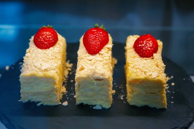 Çilekle süslenmiş nefis Napolyon keki. Pasta kafeteryasında saklanıyor. İtalyan restoranında öğle yemeği için lezzetli tatlı tabağı.