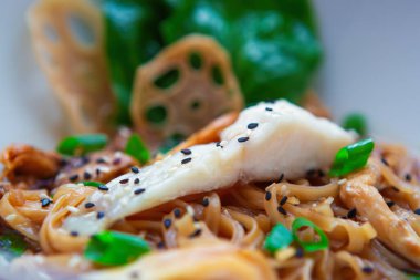 Asya deniz ürünleri. Beyaz deniz kabuğu filetosu. Soya soslu pirinç eriştesiyle pişiriliyor. Akdeniz lokantası menülerinde siyah deniz ürünleri ile servis ediliyor. 