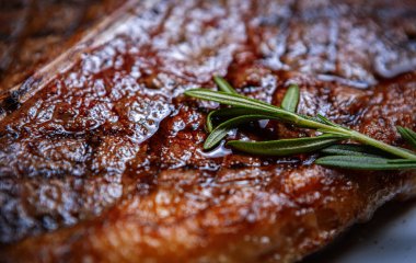 Et lokantasında akşam yemeği için ızgarada pişmiş az pişmiş biftek. Izgara domuz pirzolası. Biberiye ile hazırlanmış biftek.