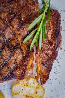 Düz katlı kaburga bifteği. Restoranda ızgarada pişmiş, biberiyeli beyaz seramik tabakta servis edilmiş nefis biftek. Amerikan lokantasında ızgara edilmiş lezzetli kırmızı et.