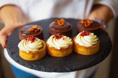 Aşçı bisküvi ve beyaz kremayla taze pişmiş kek tutuyor. Öğle yemeği için hamur işi kafede tatlılar. Atıştırmak için lezzetli tatlı bisküvisi, doğal malzemelerle pişirilmiş. Afiyet olsun.