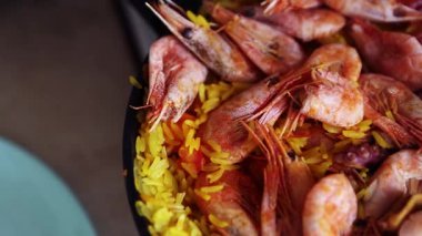 Deniz ürünleri paella 'sı pişiriyorum. Lezzetli İspanyol yemekleri mutfakta sıcak paellera tavasında kızartılıyor. Lezzetli Akdeniz mutfağı akşam yemeği için hazırlanıyor. Yaban pirinci, karides, kalamar, domates ve curcuma baharatı