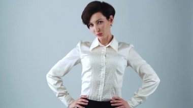 Stüdyoda gri arka planda poz veren genç ve güzel bir iş kadını. Dost canlısı beyaz kadın klasik beyaz ipek gömlek giyiyor, iş görüşmesi için kırmızı ruj sürüyor. 