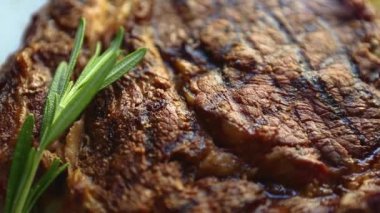 Restoranda akşam yemeği için ızgara biftek. Izgarada pişmiş, beyaz seramik tabakta servis edilmiş, yukarıdan zoom etkisi ile filme alınmış lezzetli sığır eti. Gurme kırmızı et filetosu yemek için hazır.