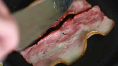 Ev mutfağında tavada kızaran pastırma şeritleri, yakın çekim 4K video klibi. Yakından ızgarada kızartılan domuz eti bantları. Kolesterollü sağlıksız yağlı yiyecekler. 