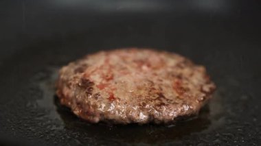 Burger pirzolası yakın çekim için kızartılıyor. Ev mutfağında sıcak tavada hamburgerler için et pişiriliyor. Biftek ızgarasının yakın çekim videosu. 