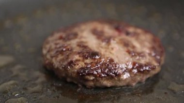 Burger pirzolası yakın çekim için kızartılıyor. Ev mutfağında sıcak tavada hamburgerler için et pişiriliyor. Biftek ızgarasının yakın çekim videosu. 