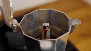 Moka tenceresi ev mutfağında kafein içeceği yapıyor. Geleneksel İtalyan kahve makinesi sabahları enerji içeceği demler. Taze kafein içeceği gaz ocağında hazırlanıyor. Yakınlaştırılmış video dudağıyla.
