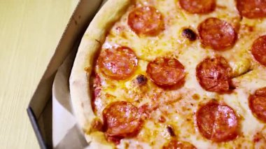 Karton kutuda İtalyan biberli pizza teslimatı. Yukarıdan çekilen geleneksel fast food çekimlerinin en üst görüntüsü. Erimiş peynirli ince hamurlu fırında pişirilmiş füme sosis.