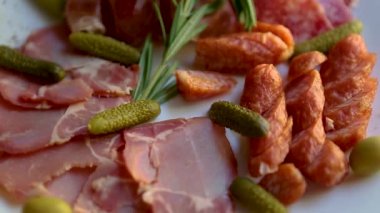 Restoranda şarap partisi için et atıştırmalıkları servis ediliyor. Lezzetli dilimlenmiş İspanyol jambonu, füme jambon, akşam yemeği için beyaz seramik tabakta servis edilen acı biberli sosis. 