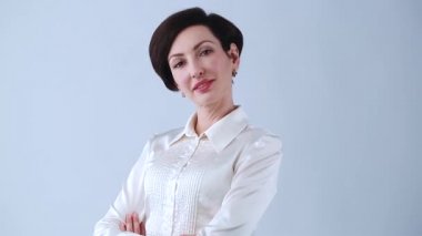 Stüdyoda gülümseyerek poz veren genç ve güzel bir iş kadını. 30 'lu yaşlarda beyaz bir kadının klasik ipek gömlek giydiği video klibi, kırmızı ruj ve makyaj kameraya gülümsüyor. 