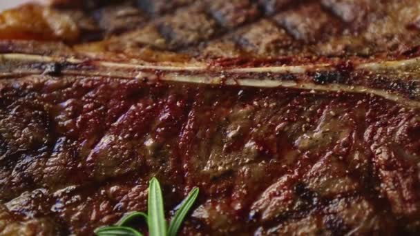 在餐馆里烤牛排当晚餐 在烤架上烹调的美味牛肉 用白色陶瓷盘食用 从上方拍摄 有放大效果 熟食红肉片调味 — 图库视频影像