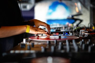 Gece kulübünde retro turntable ve vinil plaklarla müzik çalan DJ kız. Kadın disk jokeyi, gece kulübünde konser sahnesinde pikap oyuncusuna çizik attı. Sahnede profesyonel DJ 'ler var.