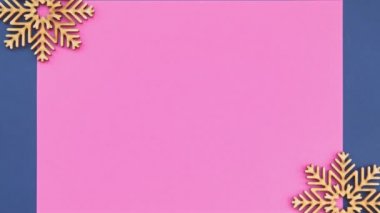 Yukardan çekilen el yapımı ahşap kar taneleri ile pembe poster şablonunun düz bir video klibi yakınlaştırma efektiyle doğrudan yukarıdan çekildi 