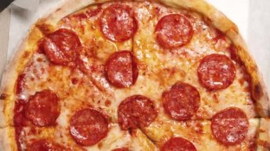 Lezzetli İtalyan pepperonili pizzalar masanın üstünde düz bir şekilde filme alınır. Akşam yemeği için karton kutuda taze fast food servis edilir. Fast food restoranından sıcak pizza. 