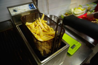 Pişirmek için fritözde çiğ patates kızartması. Fast food restoranında kızartmaya hazır patates cipsi.