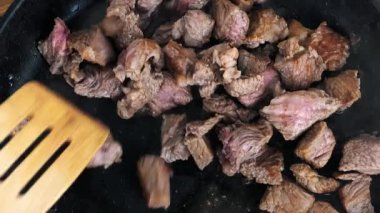 Aşçı eti tavada yavaş çekim video klipsiyle karıştırıyor. Düz yatar şekilde doğrudan filme alınıyor. Akşam yemeği için et filetosu pişiriyor, spatula ile parçaları karıştırıyor. 