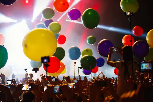 Electronic music festival in night club.Group of young people partying on dance floor in hall.Crowded nightclub with fans filming famous dj performing live on stage