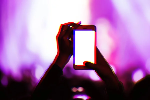 Creative double exposure illustration with concert fans filming event with smartphone camera.Fan takes pictures with mobile phone on festival in night club.Empty phones screen to place logo and text