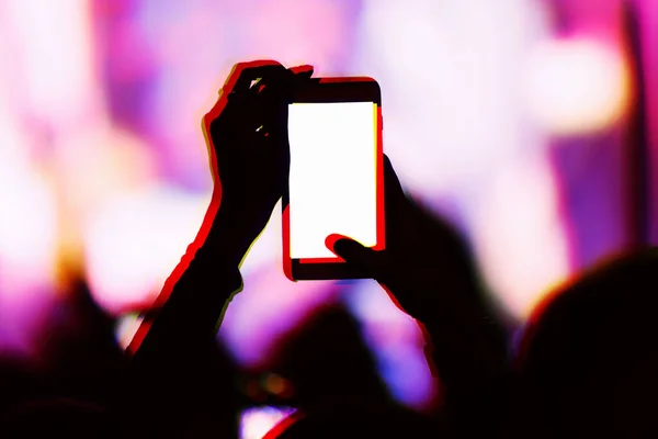 Creative double exposure illustration with concert fans filming event with smartphone camera.Fan takes pictures with mobile phone on festival in night club.Empty phones screen to place logo and text