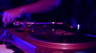 Gece kulübünde konser sahnesinde analog dj turntable. Profesyonel disk jokeyi masa başı oyuncusu, gece kulübünde çılgın bir partide müzik eşliğinde vinil plak çalıyor.