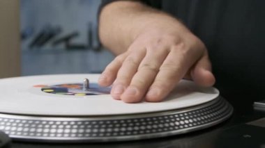 Hand of hip hop dj controlling white vinyl record disc with music on analog turntable player device. Professional disc jockey playing music on party, filmed in close up slow motion footage clip 