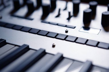 Piyano klavyeli sentezleyici aygıtı. Ses kayıt stüdyosundaki analog sentetik cihazın siyah ve beyaz anahtarları ve ses düzenleyicileri. Midi denetleyicisiyle yeni elektronik müzik oluştur