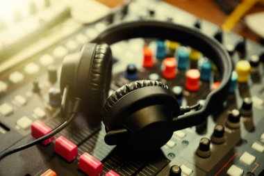 Parlak sahne ışıkları içinde profesyonel kulüp DJ kulaklıkları. Gece kulübünde kulaklık ve ses karıştırıcı paneli. Elektronik müzik gösterisi için yüksek kaliteli disk jokey ekipmanı. Gece eğlencesi etkinliği