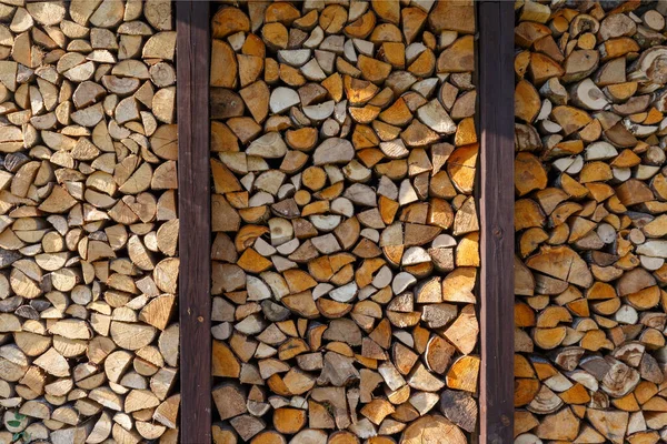 They prepare firewood for heating in winter. Firewood is neatly stacked under the roof of the shed for heating. — Stock Photo, Image