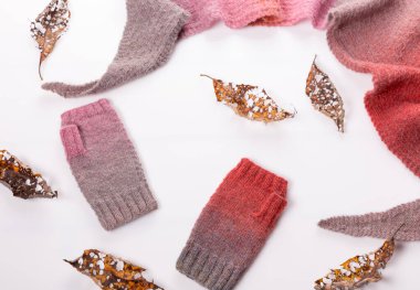 Beyaz arka planda yün şallar, gri ve pembe yün eldivenler..