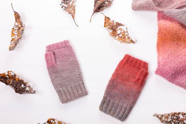 Beyaz arka planda yün şallar, gri ve pembe yün eldivenler..