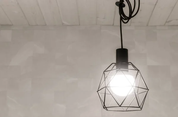 Black scandinavian style pendant lamp set against wood white ceiling and ceramic tile walls