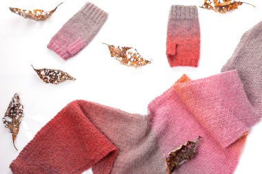 Beyaz arka planda yün şallar, gri ve pembe yün eldivenler..