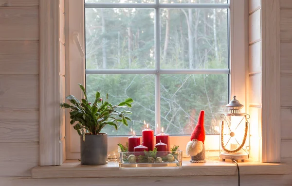 Christmas lantern, Angel, Christmas gnome, Christmas Cactus and red mug on the window of a wooden house overlooking the winter garden. — Stock Photo, Image