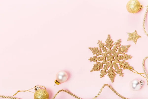 Χριστουγεννιάτικη σύνθεση. Εορταστική δημιουργική χρυσό μοτίβο, Χριστούγεννα χρυσή διακόσμηση μπάλα διακοπών με κορδέλα, νιφάδες χιονιού σε ροζ φόντο. — Φωτογραφία Αρχείου