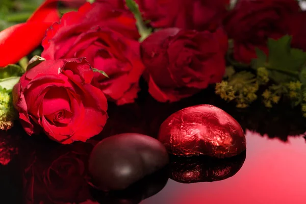 Rosas de San Valentín y chocolates en forma de corazón sobre fondo negro — Foto de Stock