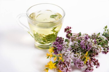 Beyaz masa zemininde kuru kekik çiçekli cam bitki çayı ve fotokopi alanı..