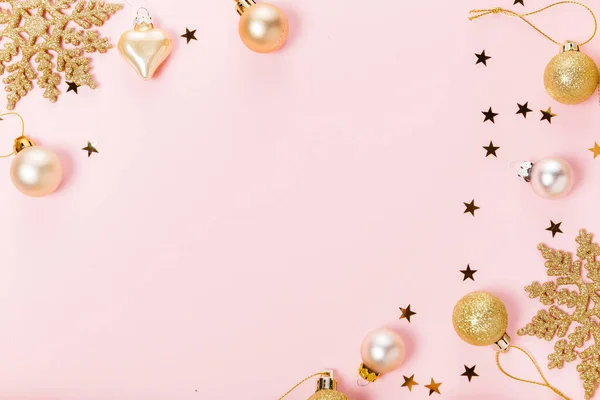 Hermosos juguetes decorativos de Navidad brillantes dorados sobre fondo rosa pastel. Lugar para el texto. — Foto de Stock