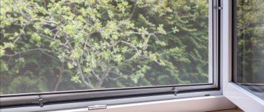 Sivrisinek ekran ve yeşil bahçe manzaralı panoramik pencere, konutlarda doğal havalandırma.