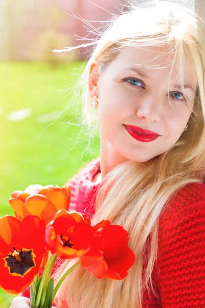 Vacker kvinna med röda blommor i sommarsolen. Skönhet Fash — Stockfoto