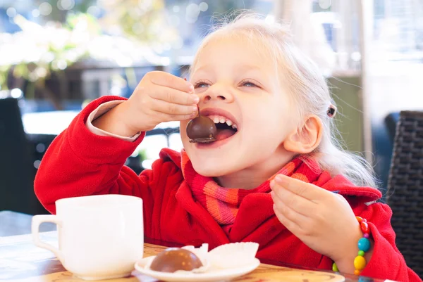 Little Girl Eats Sweets and Drinks Tea in Cafe. Royalty Free Stock Photos