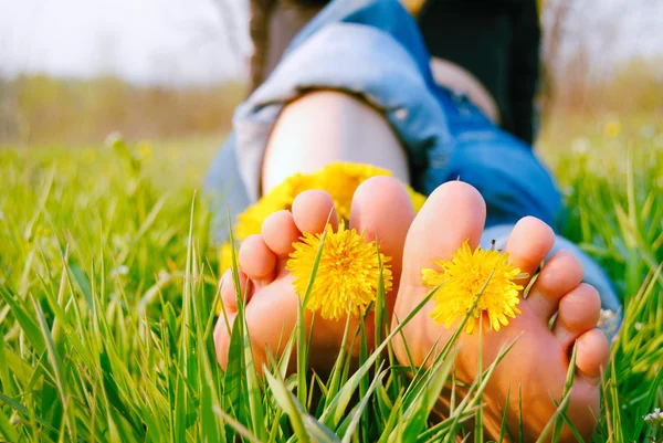 Feet of Young Woman on the Grass adorned with Dandelions Royalty Free Stock Photos