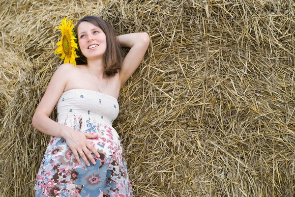 Mooie vrouw met zonnebloemen in de buurt van de hooiberg - Beauty en Fashion — Stockfoto