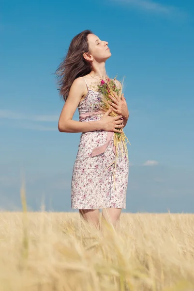 Vrouw met wilde bloemen in het tarweveld in de zomer. — Stockfoto