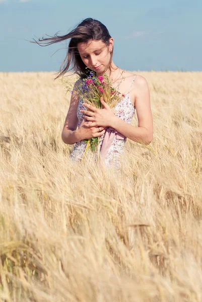 Vrouw met wilde bloemen in het tarweveld in de zomer. — Stockfoto